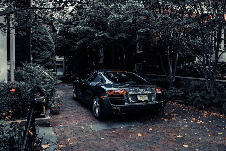 A sleek Audi R8 parked in a leafy residential driveway in Cape May, NJ, showcasing elegance and luxury.