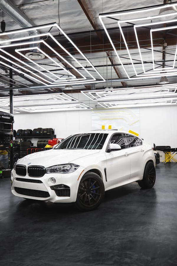 A sleek white BMW X6 parked in a contemporary auto repair shop setting.