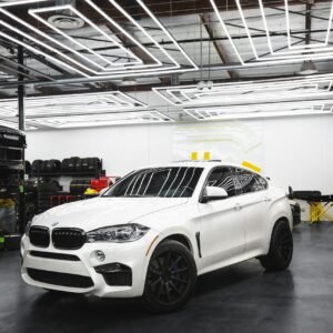 A sleek white BMW X6 parked in a contemporary auto repair shop setting.