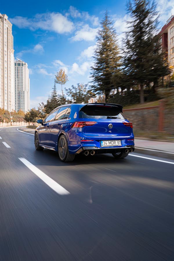 Blue sports car speeding on an urban street in Istanbul, Turkey, with city buildings in the background.