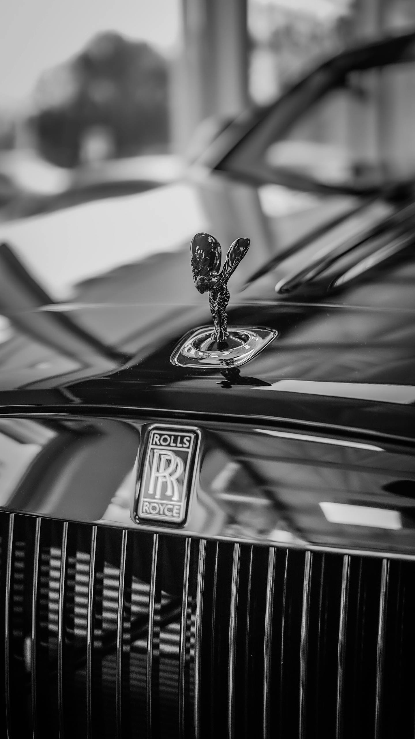Close-up of a Rolls Royce emblem on a luxury car in grayscale. Elegant vintage style.
