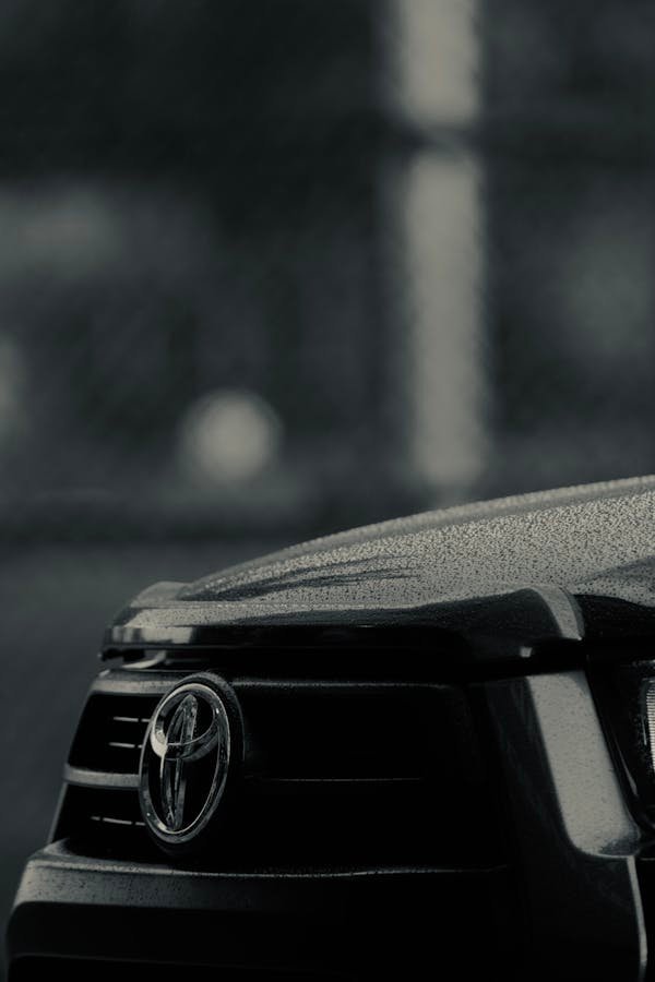 Detailed shot of a Toyota car grille covered in raindrops, showcasing texture and brand emblem.