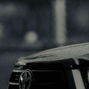 Detailed shot of a Toyota car grille covered in raindrops, showcasing texture and brand emblem.