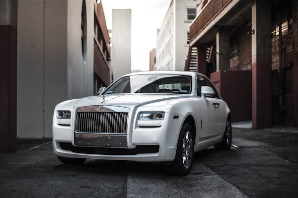 Elegant white luxury car parked in an urban alley, exuding sophistication and style.