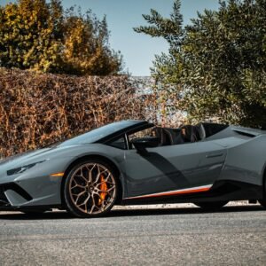 Luxury convertible sports car with orange accents parked outdoors on a sunny day.