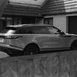 Monochrome image of a Range Rover Velar parked in a suburban driveway.