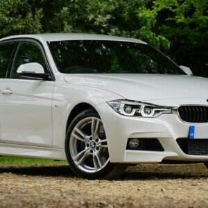 White BMW car parked on gravel path surrounded by greenery, showcasing luxury design.